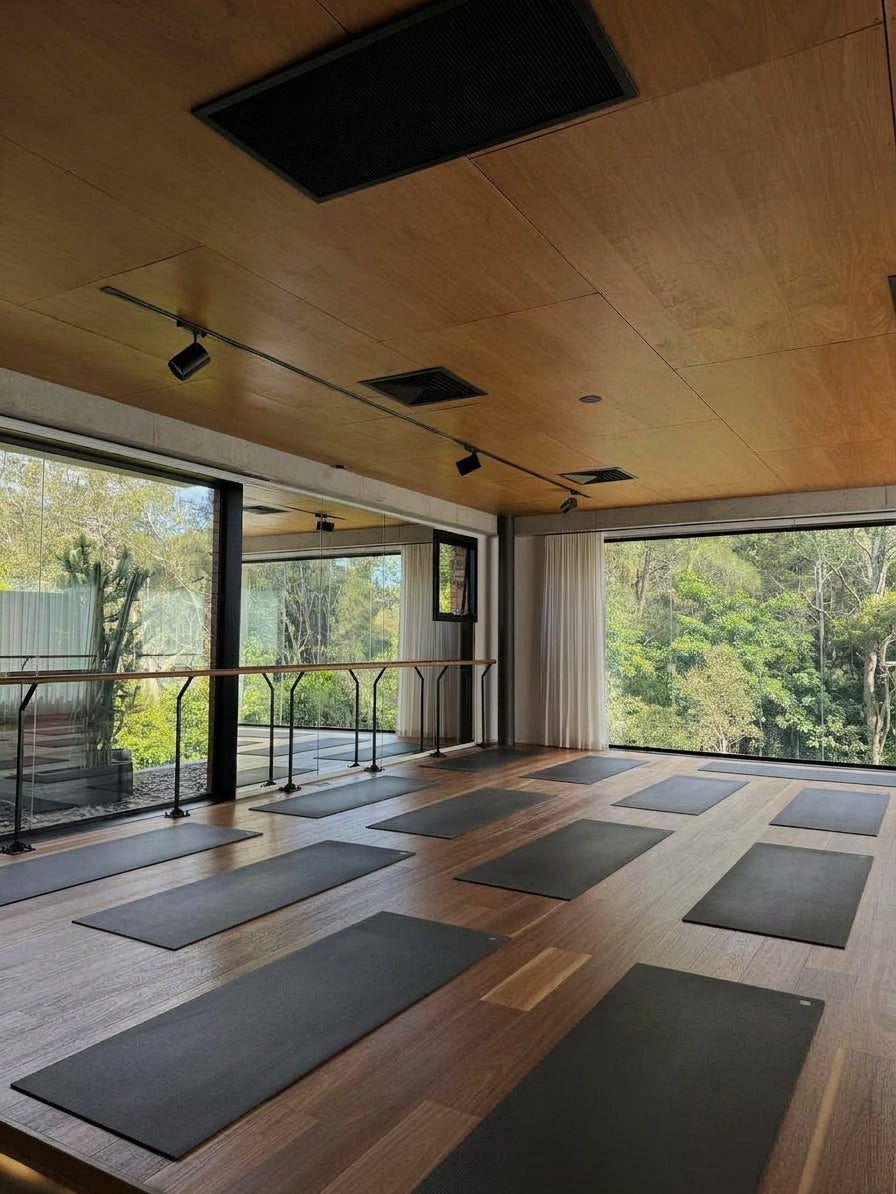 Sala de madera con grandes ventanales y esterillas preparadas para una sesión de breathwork